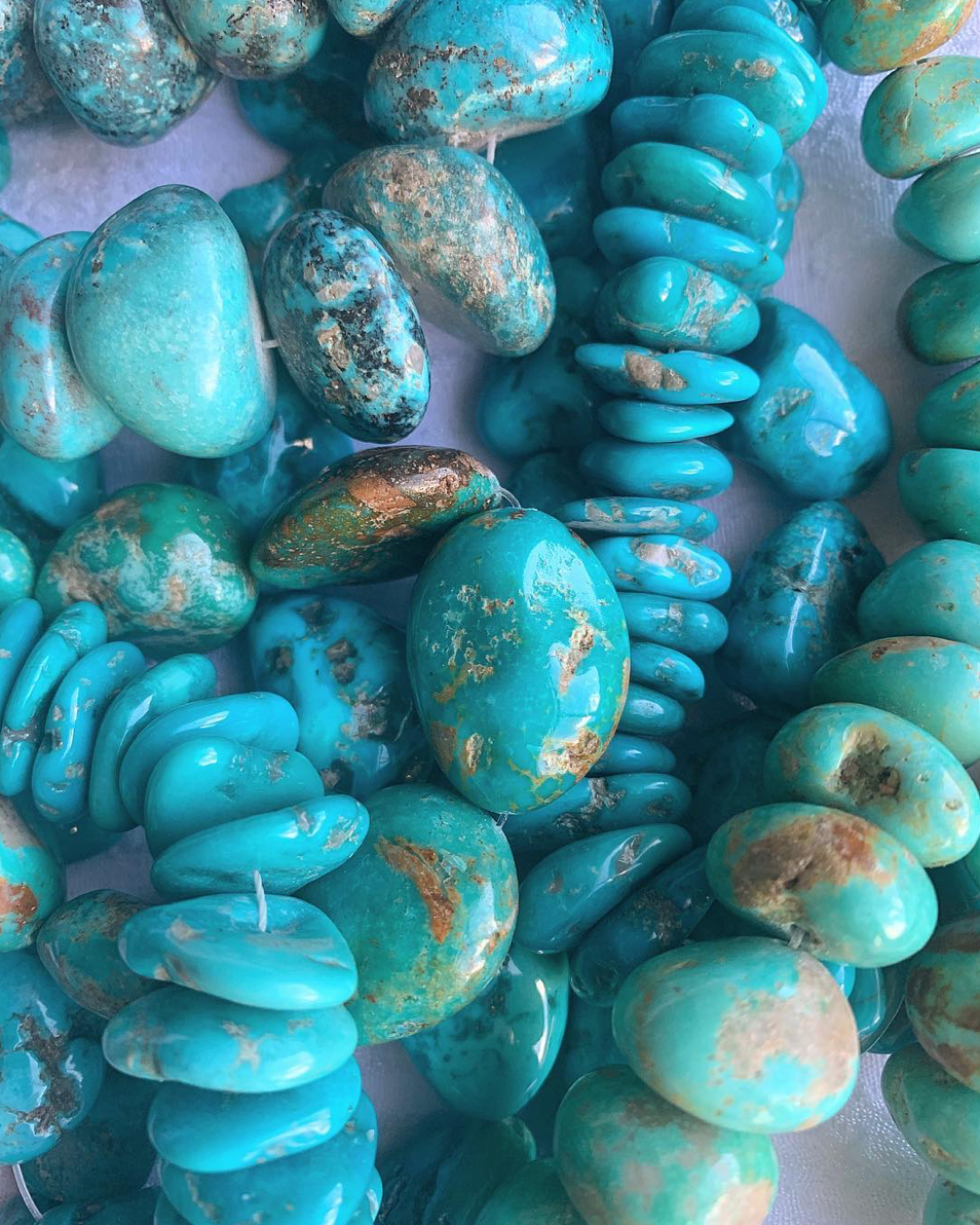 Pile of turquoise stones in an assortment of shapes, sizes, and shades of blue.